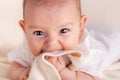 Small cute funny baby infant teething with face expression hands and fingers in mouth sore gums Royalty Free Stock Photo