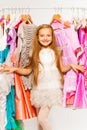Small cute girl standing between hangers in shop Royalty Free Stock Photo
