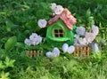 Small cute green house with roses, small fence, hearts and watering can in the garden Royalty Free Stock Photo