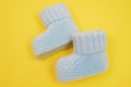 Small cute knitted booties for newborn baby. Baby shoes on yellow background. Royalty Free Stock Photo