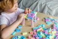 Small cute preschooler girl playing with colorful toy building blocks, sitting at the table Royalty Free Stock Photo