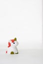 Small cute white unicorn toy with coral hair on a white empty background. Isolated. Copy space. Symbol. Kid. Colour. Vertical