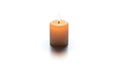 A small, cylindrical, beige candle burns with a bright, steady flame. It stands upri Royalty Free Stock Photo