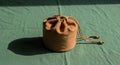 A small, cylindrical brown drawstring pouch made of fabric sits on a green, textured Royalty Free Stock Photo