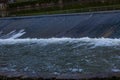 Small dam, also called a weir with water flowing over it Royalty Free Stock Photo