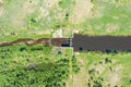 Small dam on a flat river flowing through green meadows, top aerial view Royalty Free Stock Photo