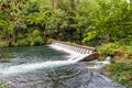 Small dam with spillways on the river Eume with shores covered w