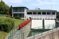 Small dam used to regulate and direct water to hydropower plant with freshly cut grass and flowers in front