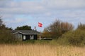 a small Danish wooden house is idyllically situated in the dunes on the beach and has hoisted the Danish flag Royalty Free Stock Photo