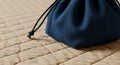 A small, dark blue drawstring pouch rests on a quilted beige surface. The pouch Royalty Free Stock Photo