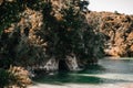 small dark cave in the rock in the calm waters of the calm sea surrounded by forest and trees in the shadows of sunset Royalty Free Stock Photo