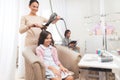 A small dark-haired girl sits in the beauty salon chair. The hairdresser dries the hair to the girl with a hairdryer. Royalty Free Stock Photo