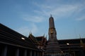 A small, decorated tower stands in the courtyard of Wat Pho Monastery in the evening