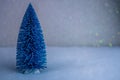 Small decorative blue Christmas tree with artificial snow on light blue background Royalty Free Stock Photo