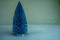 Small decorative blue Christmas tree with artificial snow on light blue background Royalty Free Stock Photo