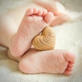 Small delicate little feet to keep the wooden heart Royalty Free Stock Photo