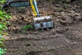 Small diesel excavator claw or bucket, resting on the ground on a dig site. Close up shot, sunny day, no people