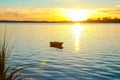 Small dinghy at anchor in silhouette back-lit by intense sunrise
