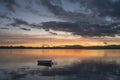 Small dinghy in bay with reflected orange golden hour light in Tauranga New Zealand