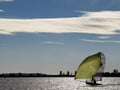 A small dinghy with large yellow sail under a blue sky sailing on a lake