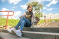 small dog and her owner a teenager girl are sitting on the steps of the stairs Royalty Free Stock Photo