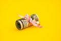 Small dollar gift, Bundle of bills of one hundred dollars tied with a pink ribbon. Dollars isolated on yellow background Royalty Free Stock Photo
