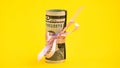 Small dollar gift, Bundle of bills of one hundred dollars tied with a pink ribbon. Dollars isolated on yellow background Royalty Free Stock Photo
