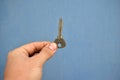 Small door key in hand on a blue background Royalty Free Stock Photo