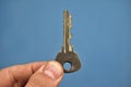 Small door key in hand on a blue background