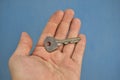 Small door key in hand on a blue background Royalty Free Stock Photo