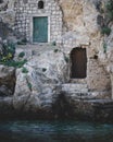 a small doorway in the wall and rocks near water and rocks