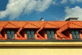 Small dormer windows in a red tiled roof against blue sky background Royalty Free Stock Photo