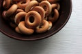 Small dry bagels for kids in brown ceramic bowl on white wooden background. Healthy snack Royalty Free Stock Photo