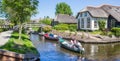 Small electric motorboats passig by a historic white house in Giethoorn