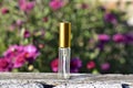 Small empty perfume sample bottle on a background of flowers