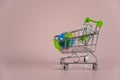 Small empty shopping cart with globe on pink background