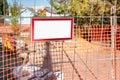 Small empty sign board in red frame hanging on metal fence Royalty Free Stock Photo
