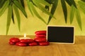 Small empty slate in width to write a message posed on the bamboo floor with red stones columns in the lifestyle Zen with a candle Royalty Free Stock Photo