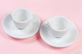 Small empty white coffee cups with handles on the saucer