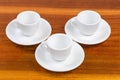 Small empty white coffee cups on saucers on wooden surface Royalty Free Stock Photo