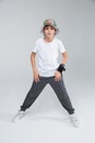 A small boy stands with his legs wide apart. On a gray background. Royalty Free Stock Photo