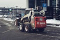 Small excavator bobcat working on the street and cleaning in the city after a snowfall Royalty Free Stock Photo