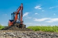 A small excavator is building a new road on a green field. copy space Royalty Free Stock Photo