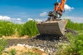 A small excavator is building a new road on a green field. copy space Royalty Free Stock Photo