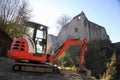 Small excavator on a consruction site hill in front of an ancient castle ruin Royalty Free Stock Photo