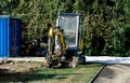 A small excavator on a construction site against a background of green trees Royalty Free Stock Photo