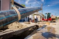 Small excavator with front blade is carry long HDPE pipe over trench, water supply network Royalty Free Stock Photo