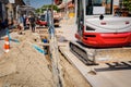 Small excavator with front blade is carry long HDPE pipe over trench, water supply network Royalty Free Stock Photo