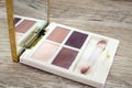 Small eyeshadow palette with a mirror on a wooden background.