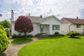 Small family house with green lawn and decorative tree in front.